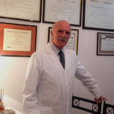 El Dr. César Benito Sáenz de pie en su consultorio con sus diplomas de fondo